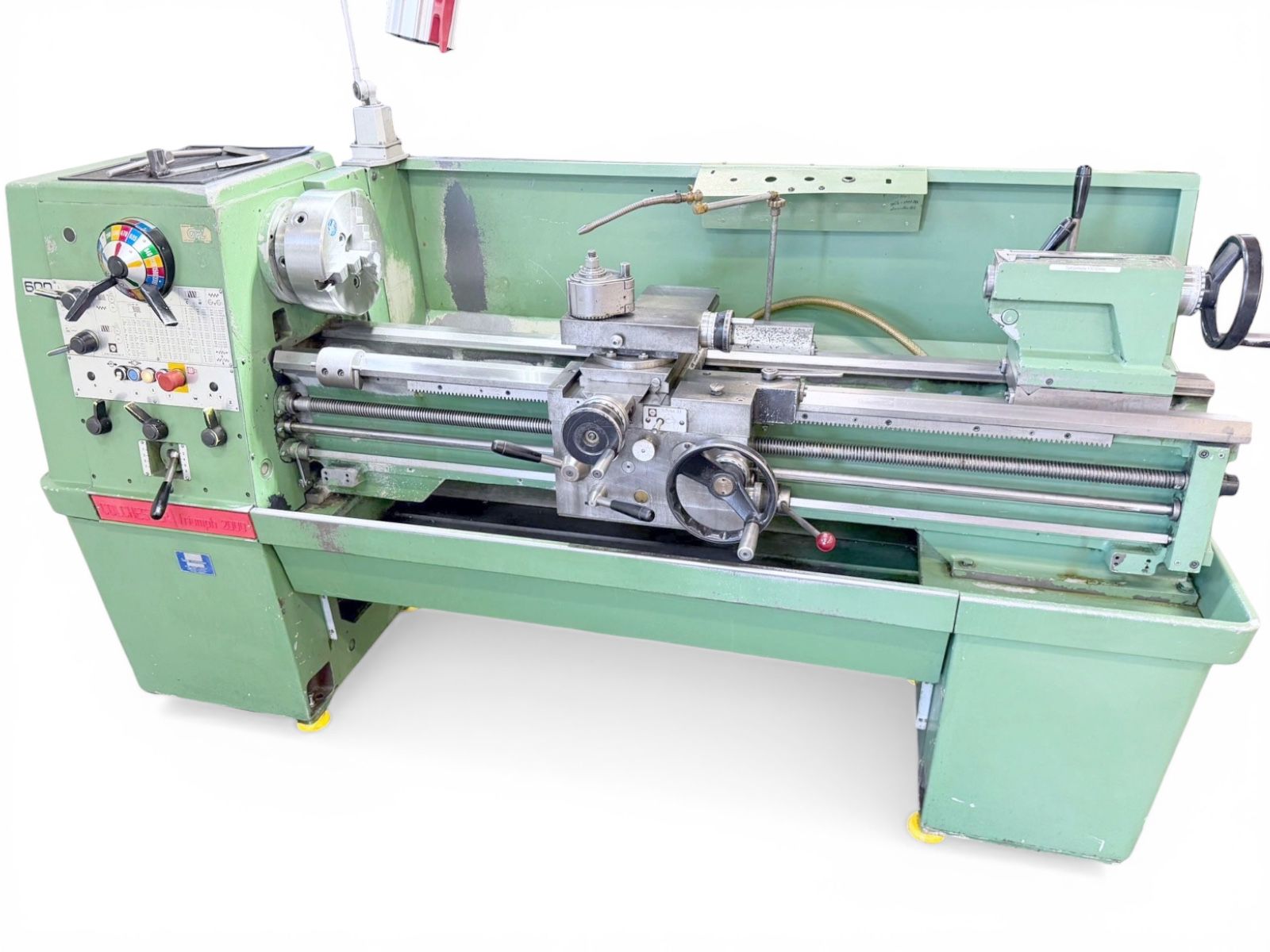 Industrial green metal lathe machine with control panel on left and hand cranks, used for turning cylindrical parts in a workshop